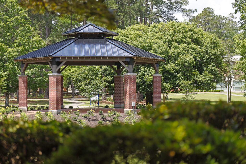 SCC Bell Pavilion surrounded by green trees and landscaped flower beds.