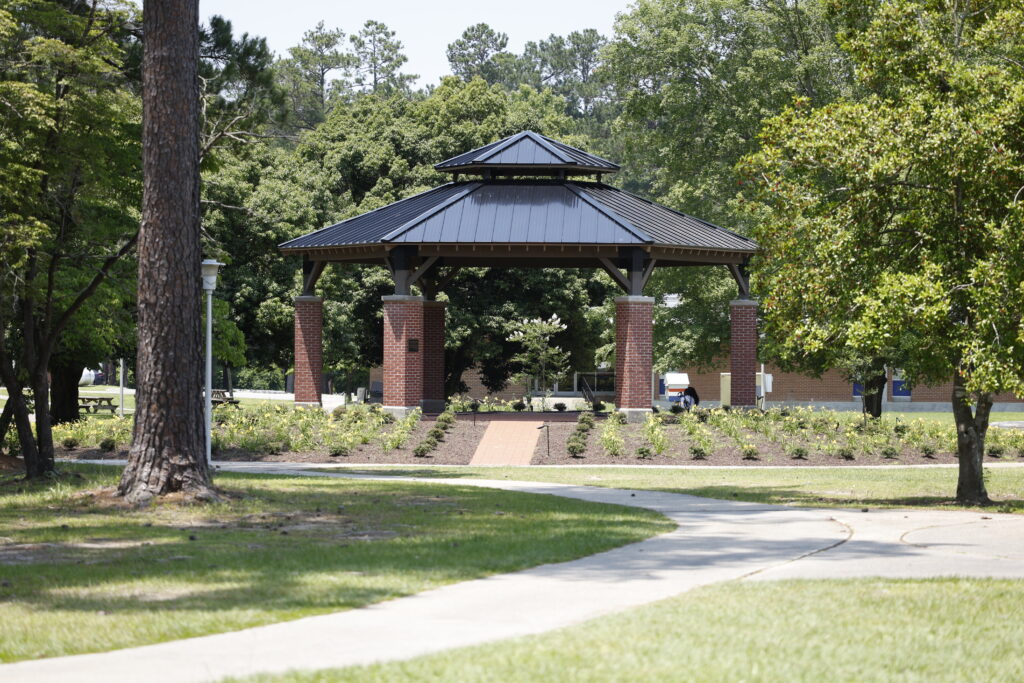 Walkway leading to the SCC Bell Pavilion, surrounded by trees and campus greenery.