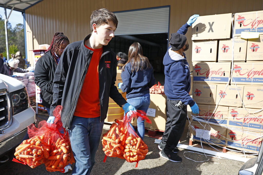 Noah Powell carries food to a car at the Facts of Life distribution center.