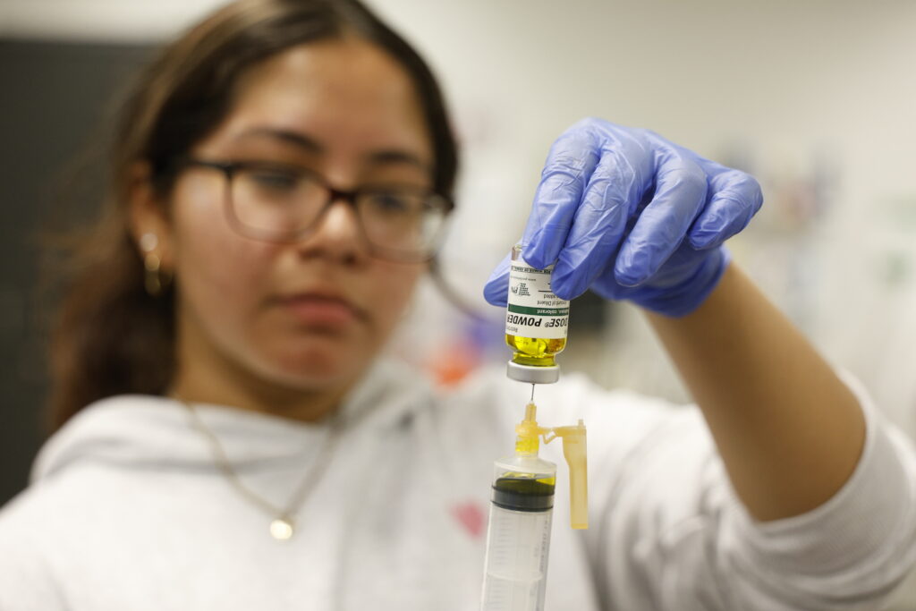 Summer Camp student uses syringe to extract solution from vial
