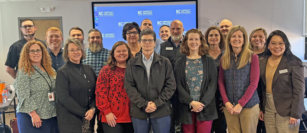 Cristian Wood (in red top) stands with NC community college representatives at their first PTE Alignment Project meeting in Raleigh.