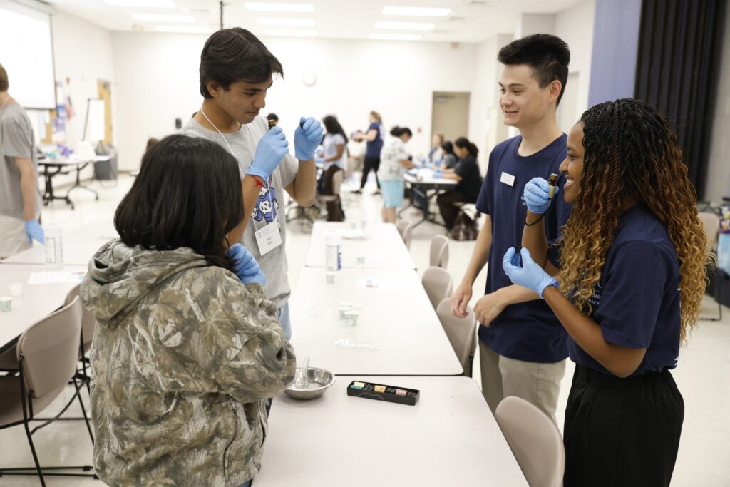 Four PILLS Academy students from 2025 standing around a table participating in an activity.