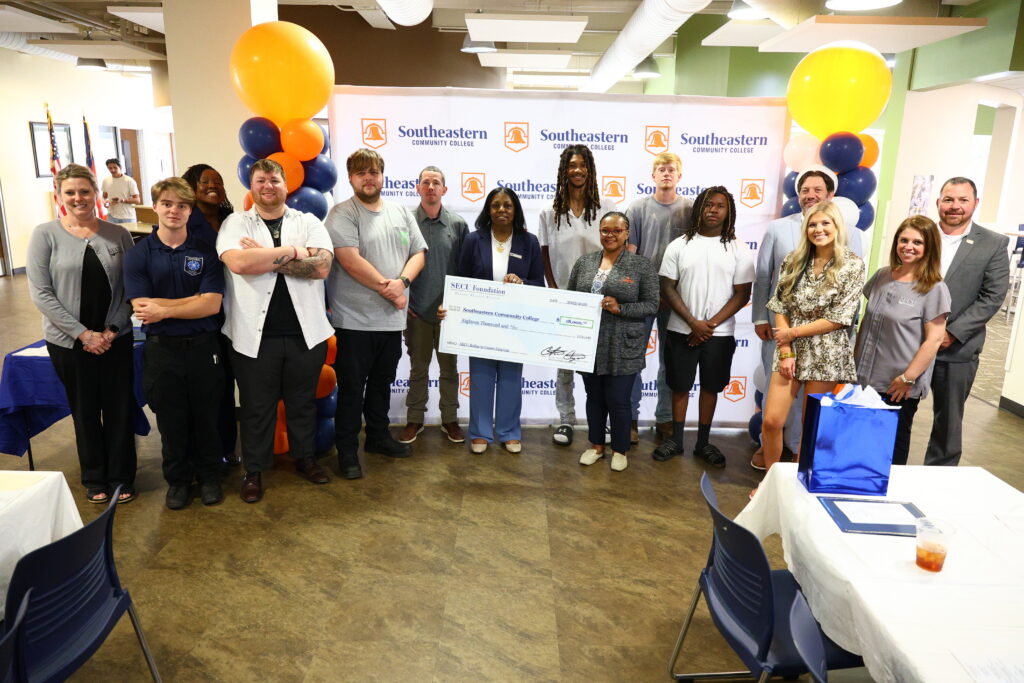 SECU scholarship recipients standing with SCC employees and SECU Foundation holding an $18,000 check.