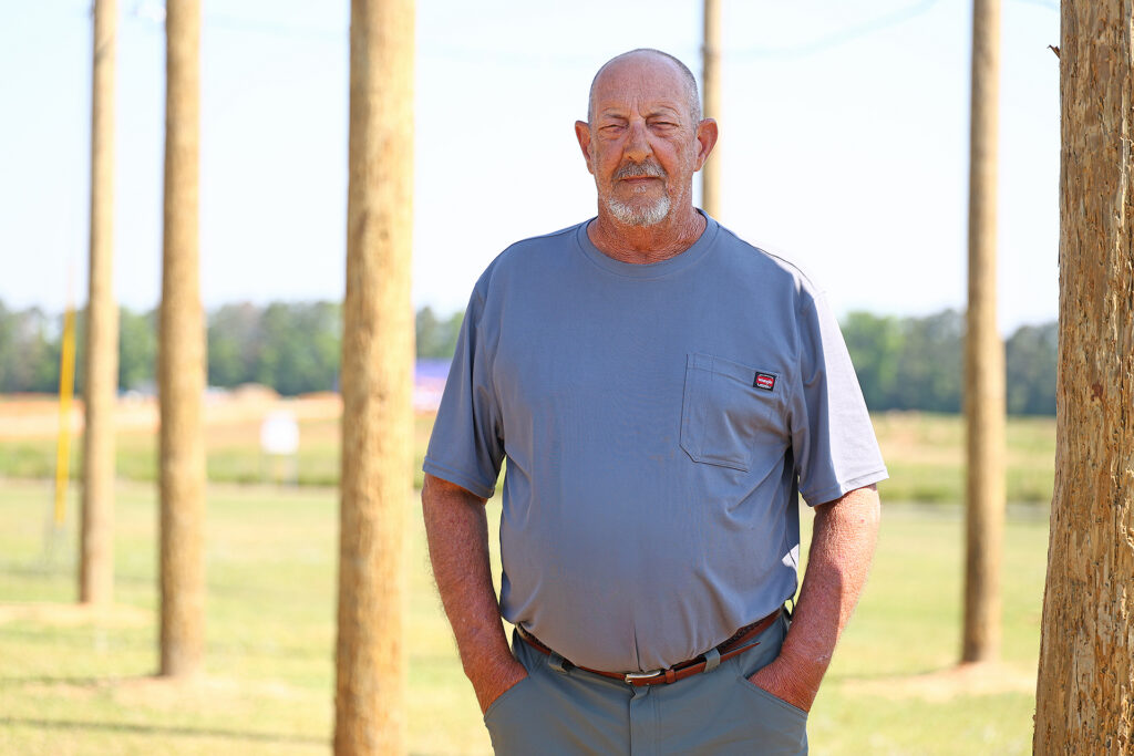 Electrical Lineman Program Coordinator and Instructor David Ward stands near the electrical lineman power pole lab area on campus.