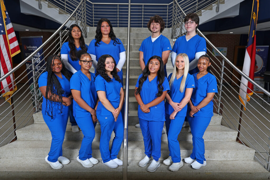 Nurse Aide I graduates stand on the stairs in A-Building.