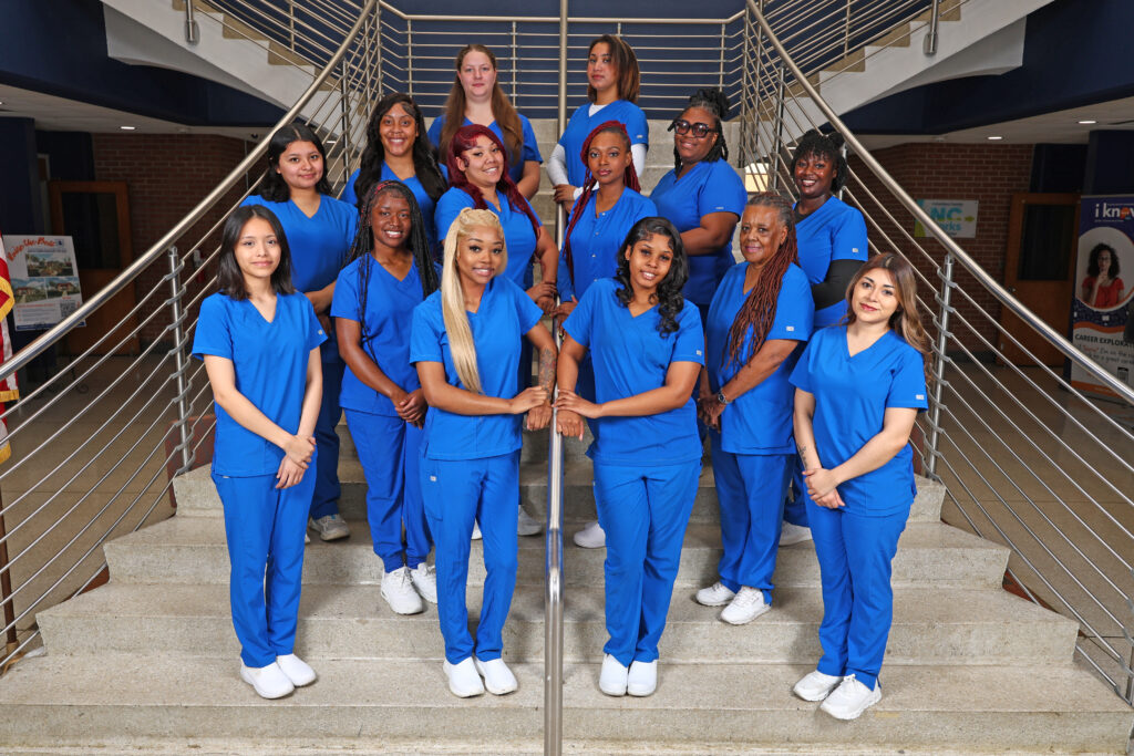 Nurse Aide I graduates stand on the stairs in A-Building.