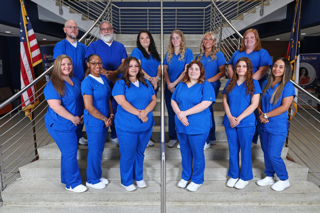 Nurse Aide I graduates stand on the stairs in A-Building.