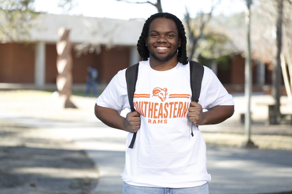 Isaiah Johnson smiling and standing with a backpack on and SCC shirt.
