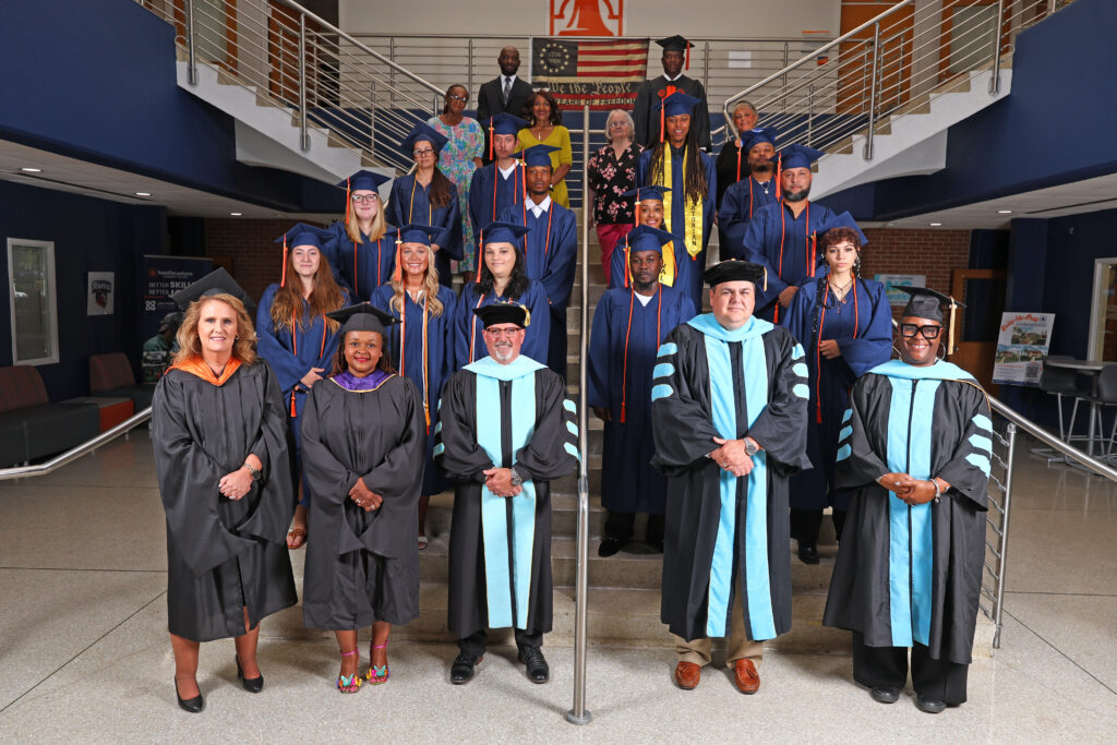 SCC leadership stands with the Transitional Studies program class of 2026 on the stairs in A-building.