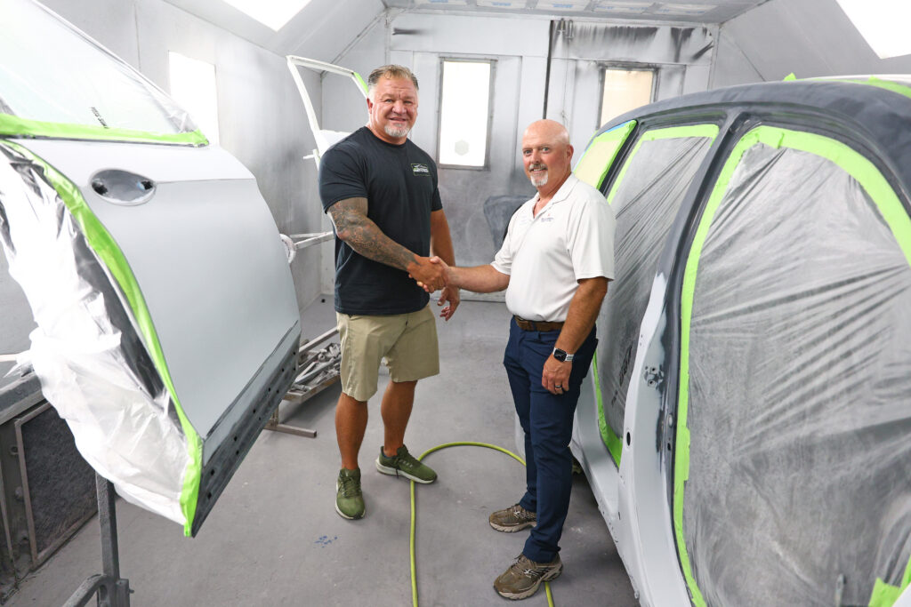 Kevin Harrelson, left, shakes hands with Dr. Chris English inside one of the painting facilities at Southeastern Paint and Body in Chadbourn.