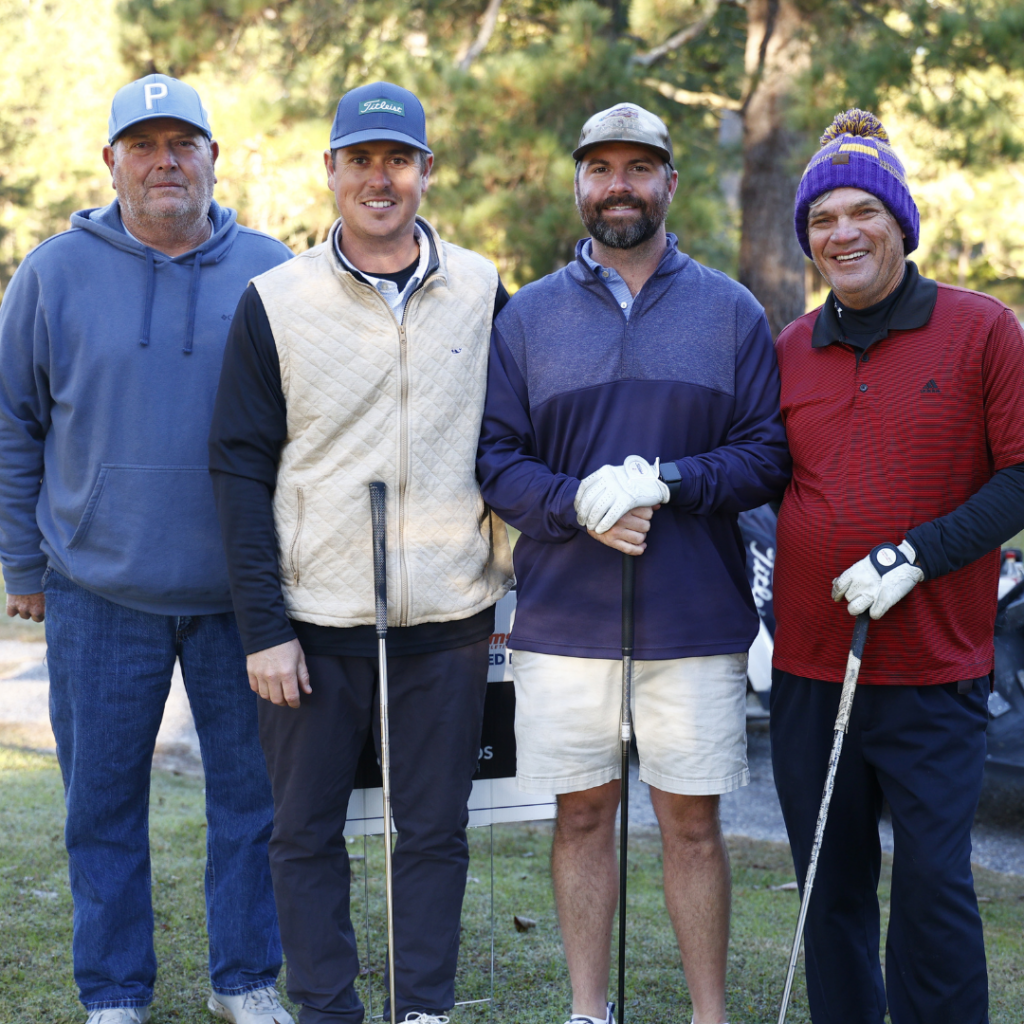 Golf Tournament team standing and smiling with golf clubs