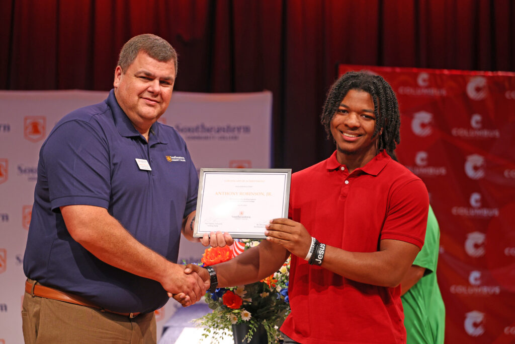 Dr. Brandon Jenkins presents a certificate at the high school summer camp certificate ceremony in the SCC auditorium.