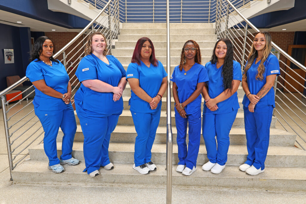 SCC phlebotomy graduates stand on the stairs in A-building on campus.