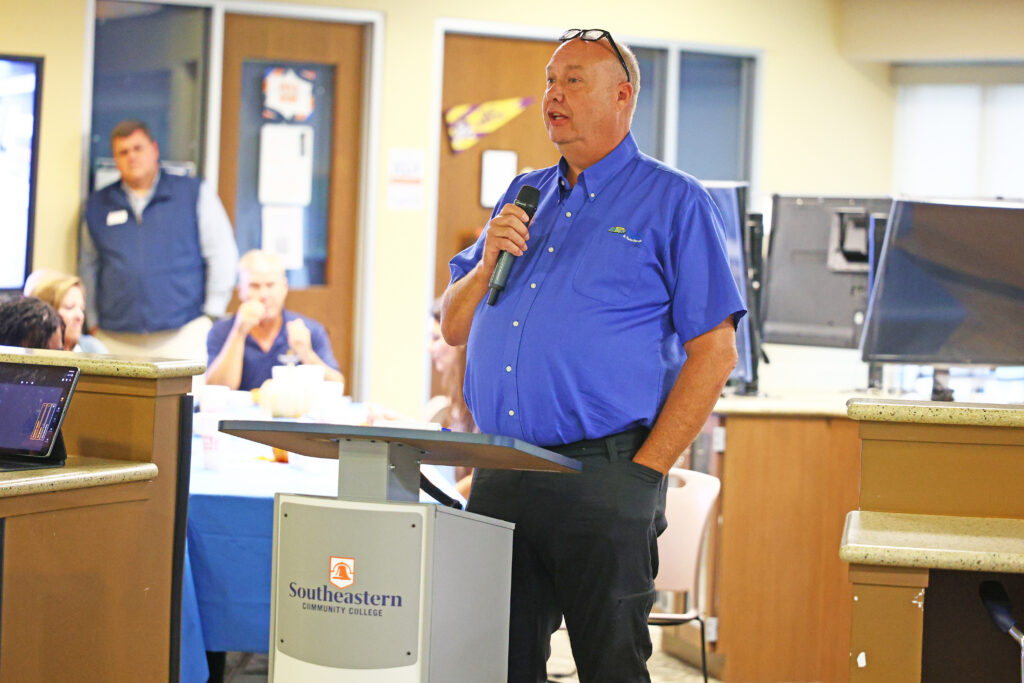 Gary Collier, of Black's Tire Service, speaks to the advisory council meeting audience about apprenticeships.