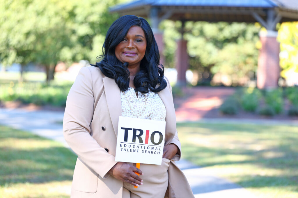 Dr. Leslie Brown, Director of ETS, holds a sign outside on campus.